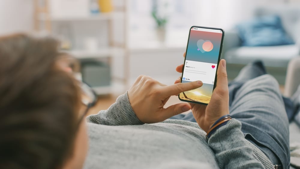 Man on couch browsing social media on his phone